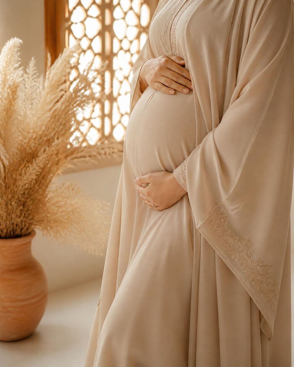 Expectant parent cradling their belly, wrapped in soft cream linen